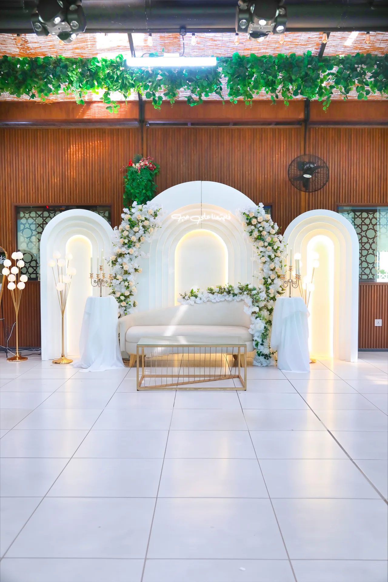 White arches and floral stage across the hall