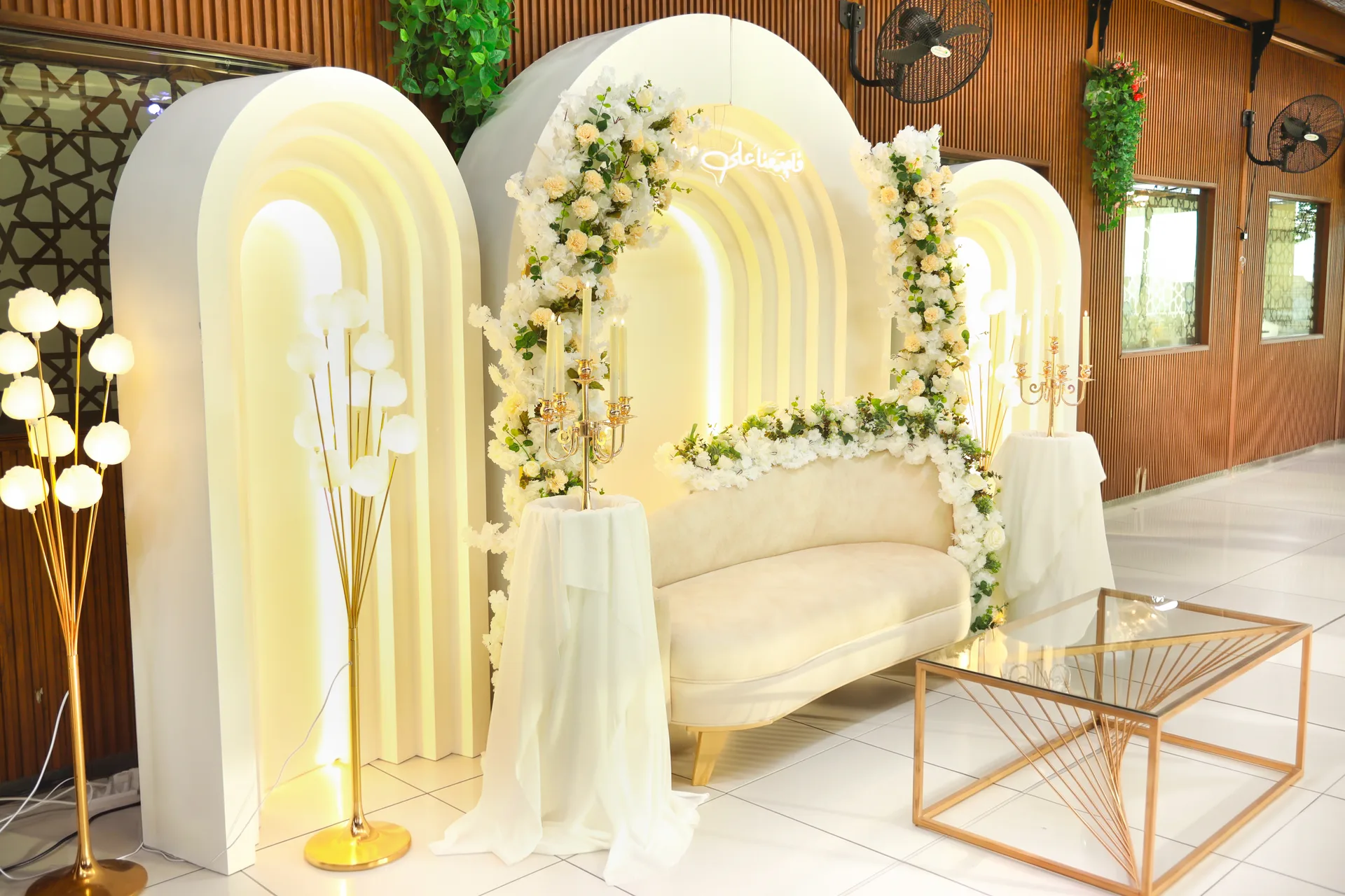 Lit white arches with floral garland and lounge