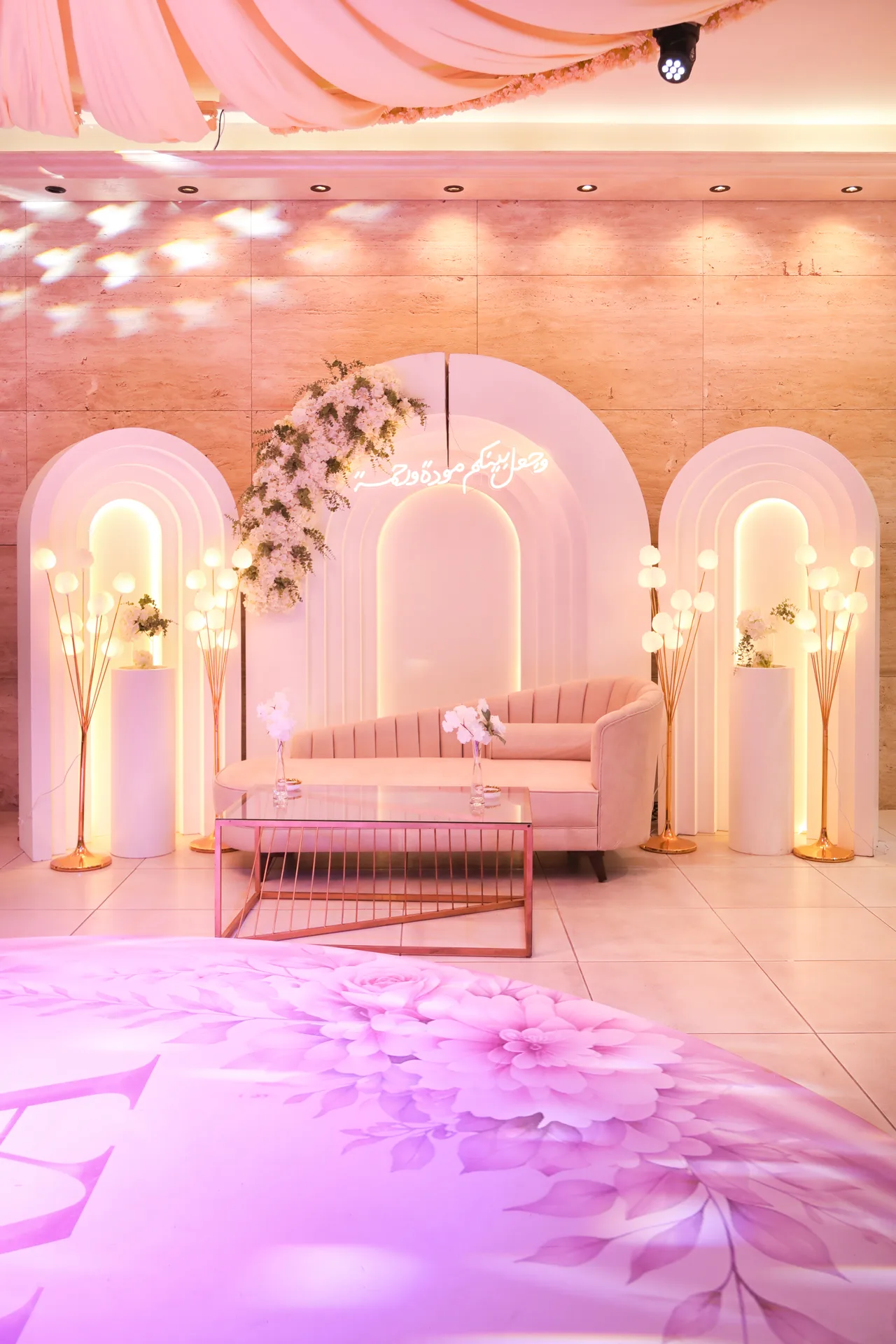 Pink-lit lounge stage with floral arches